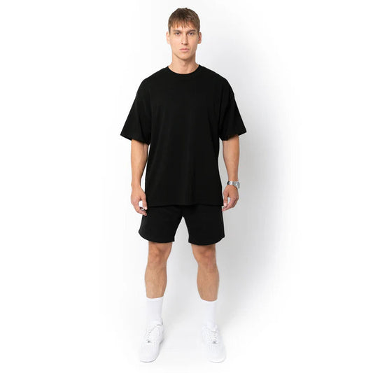 Person wearing a black oversize tee with white shoes on a white background